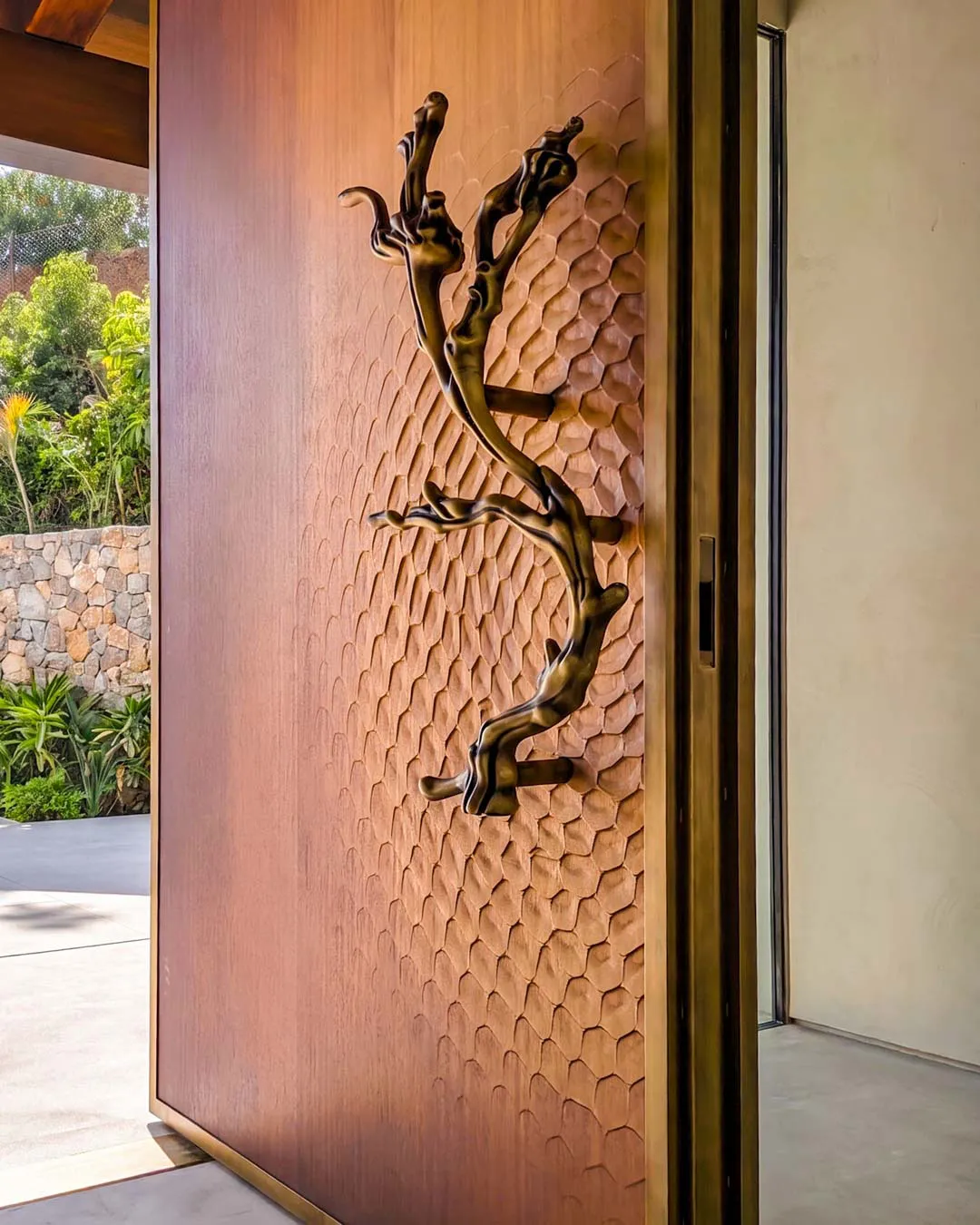 Maniglia scultorea a forma di ramo su pannello fresato a nido d'ape di una porta d'ingresso su misura, Metalbril